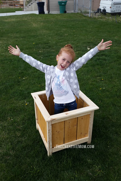 wood box planter outside with girl inside box